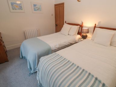 A bedroom with two beds and a lamp at 1 Rowes Cottages Penzance