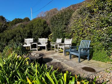 A garden with chairs and a stone patio at 1 Rowes Cottages Porthgwarra