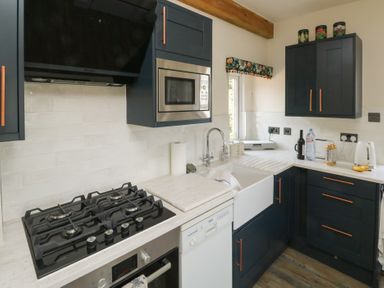 A kitchen with a sink, stove, and microwave at 13 School Road, Newton Abbot