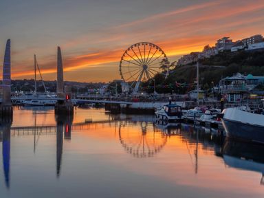 A harbor with boats and a ferris wheel at sunset at 13 School Road in Kingskerswell