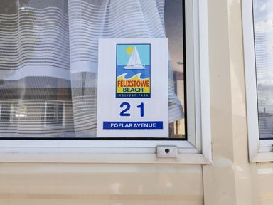 A window showing a sign for 21 Poplar Avenue at Felixstowe Beach Holiday Park