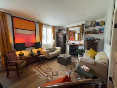 A living room with a sofa, armchair and fireplace at Bohemian Beach Cottage in Bournemouth