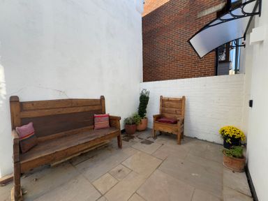 An outdoor seating area with benches and potted plants at Bohemian Beach Cottage in Bournemouth