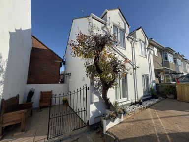 An outdoor view of a house with a tree and gated entrance at Bohemian Beach Cottage in Bournemouth