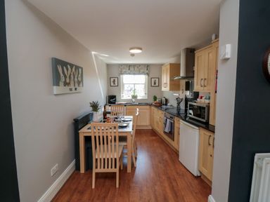 A kitchen with cooking appliances and a dining table at Stanton House - Abbey View, Flat 3