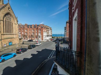 A view of a street with buildings and cars, with the ocean in the distance at Stanton House - Abbey View, Flat 3