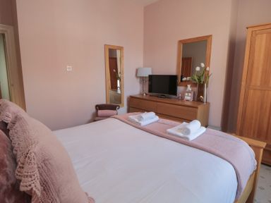 A bedroom with a bed, television and flowers at Stanton House - Abbey View, Flat 3