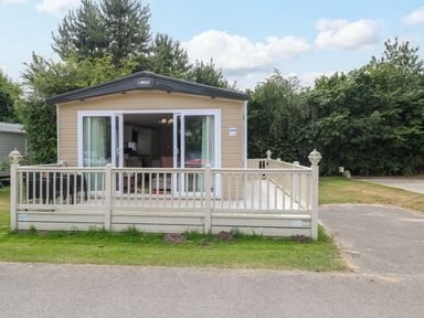 A park home with decking and trees at 17 Castle Walk in Great Yarmouth