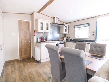 A kitchen with cabinets and dining area at 17 Castle Walk Great Yarmouth