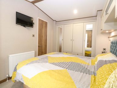 A bedroom with a bed, wardrobe, and television at 17 Castle Walk in Great Yarmouth