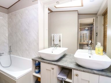 A bathroom with a bathtub and dual wash basins at 17 Castle Walk in Great Yarmouth