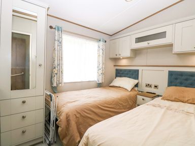 A bedroom with two beds and a mirror at 17 Castle Walk in Great Yarmouth