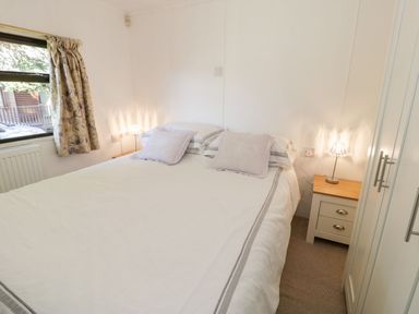 A bedroom with a double bed and curtains at Summertime Lodge Rhyd-y-Foel near Abergele