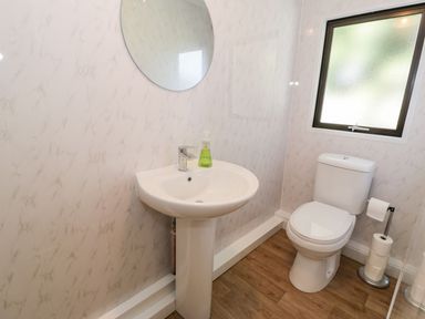 A bathroom with a sink, toilet and mirror at Summertime Lodge in Rhyd-y-Foel near Abergele