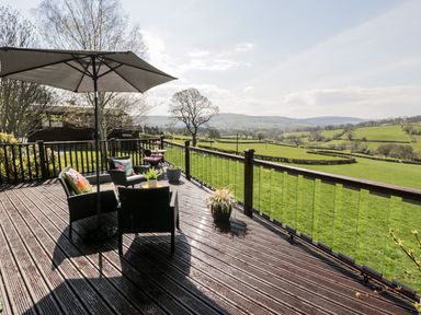 An outdoor seating area with chairs and a parasol at Summertime Lodge in Rhyd-y-Foel near Abergele