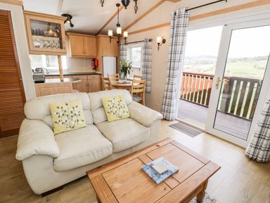 A living room with sofa and dining area at Alpine Lodge Rhyd-y-Foel near Abergele