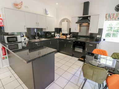 A kitchen with worktop, dining table, and appliances at Raglan Lodge in Monmouth