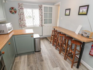 A kitchen with a counter and bar stools at Hillside Cottage