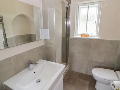 A bathroom with a sink, mirror, shower, and toilet at Hillside Cottage 