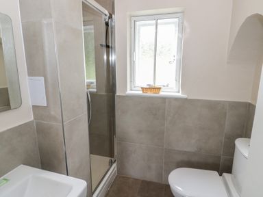 A bathroom with a shower, toilet, and sink at Hillside Cottage
