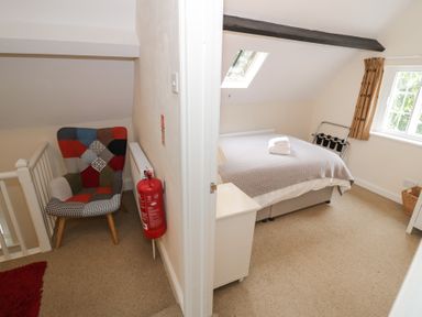 A bedroom with a bed and armchair at Hillside Cottage