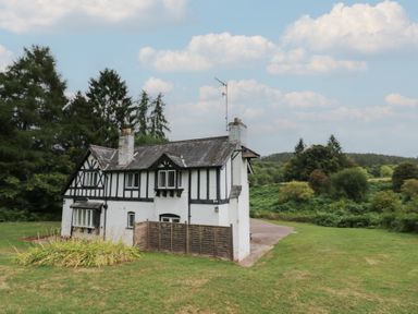 A house with a garden and trees at Hillside Cottage