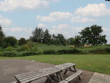 An outdoor area with a wooden table and benches at Hillside Cottage