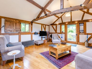 A living room with wooden beams two armchairs a coffee table and a television at The Cider Mill in Westhope near Leominster