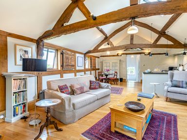 A living room with wooden beams a sofa armchair coffee table and bookshelf at The Cider Mill in Westhope near Leominster