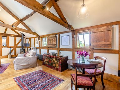 A sitting area with armchair a painted chest a round wooden table with chairs and wooden beams on the ceiling at The Cider Mill Westhope near Leominster