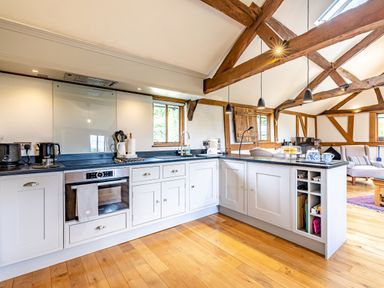 A kitchen with white cabinets wooden beams and wooden floor at The Cider Mill in Westhope near Leominster