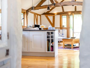A kitchen island with a cake stand and tea set in an open living area with wooden beams and furniture at The Cider Mill Westhope near Leominster