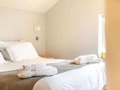 A bedroom with a bed made with white linens and folded towels at The Cider Mill in Westhope near Leominster