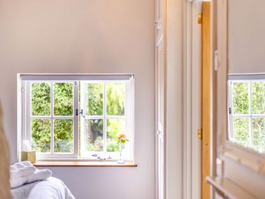 A window with six panes next to a bed with folded towels on it and a single flower in a vase at The Cider Mill in Westhope near Leominster
