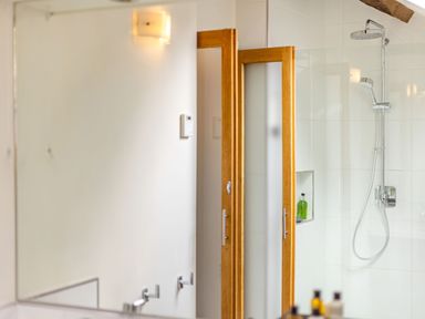 A bathroom with a shower area and wooden framed frosted glass doors at The Cider Mill in Westhope near Leominster
