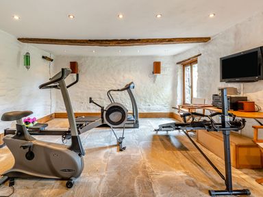 A home gym with exercise equipment and a television on the wall at The Cider Mill in Westhope near Leominster