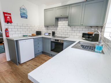 A kitchen with a sink, fridge, oven and microwave at 23 The Maltings in Weymouth