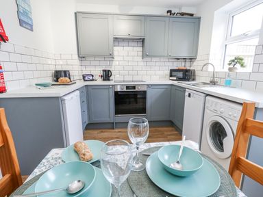A kitchen with appliances and dining setup at 23 The Maltings in Weymouth