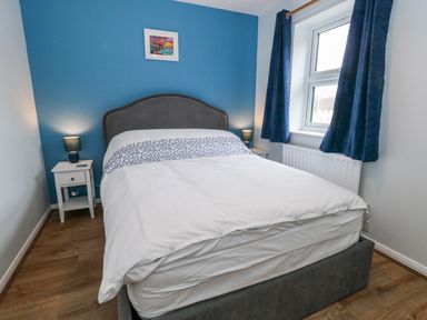 A bedroom featuring a bed, nightstand, lamp and window at 23 The Maltings Weymouth