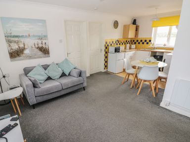 A living room with a couch and a kitchen area at Chalet 26 in Scurlage