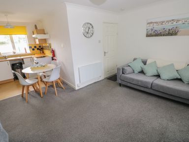 A living room with a dining area and kitchen in Chalet 26 Scurlage