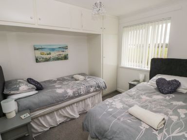 A bedroom with two beds and a nightstand at Chalet 26 in Scurlage