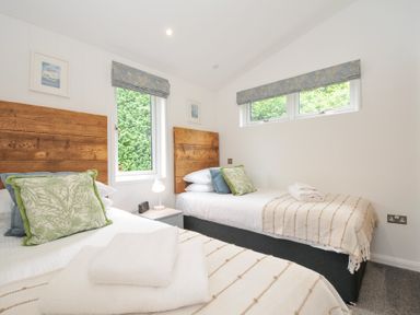 A bedroom with two beds and windows at 3 Meadow Retreat in Liskeard
