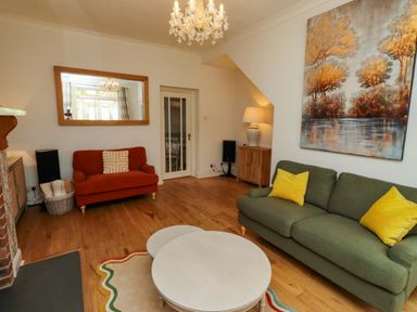 A living room with orange and green sofas and a coffee table at Rose Briar Cottage in Morpeth