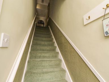 A staircase with green carpet and wall decor at Rose Briar Cottage in Morpeth
