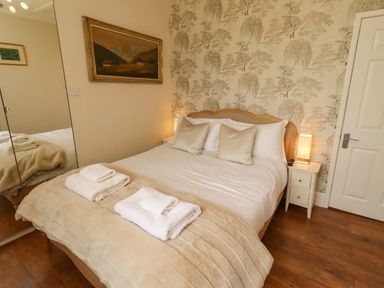 A bedroom with a bed and bedside table at Rose Briar Cottage in Morpeth