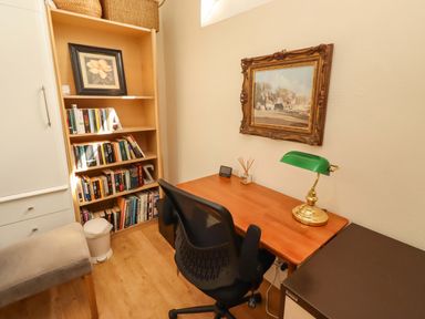 An office with a desk, chair, and bookshelf at Rose Briar Cottage in Morpeth