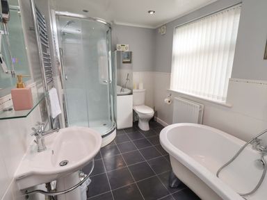 A bathroom with a shower, bathtub, toilet, and sink at Rose Briar Cottage in Morpeth