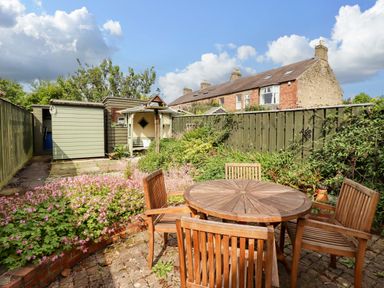 A garden with a table and chairs at Rose Briar Cottage in Morpeth