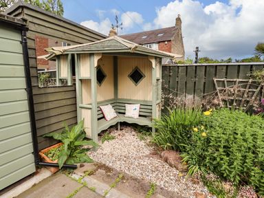 A garden seating area with a wooden structure at Rose Briar Cottage Morpeth